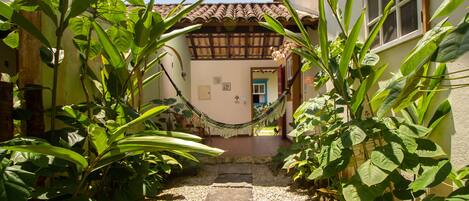 A pathway leading to a house with a tiled roof and a hammock hanging between two trees.
