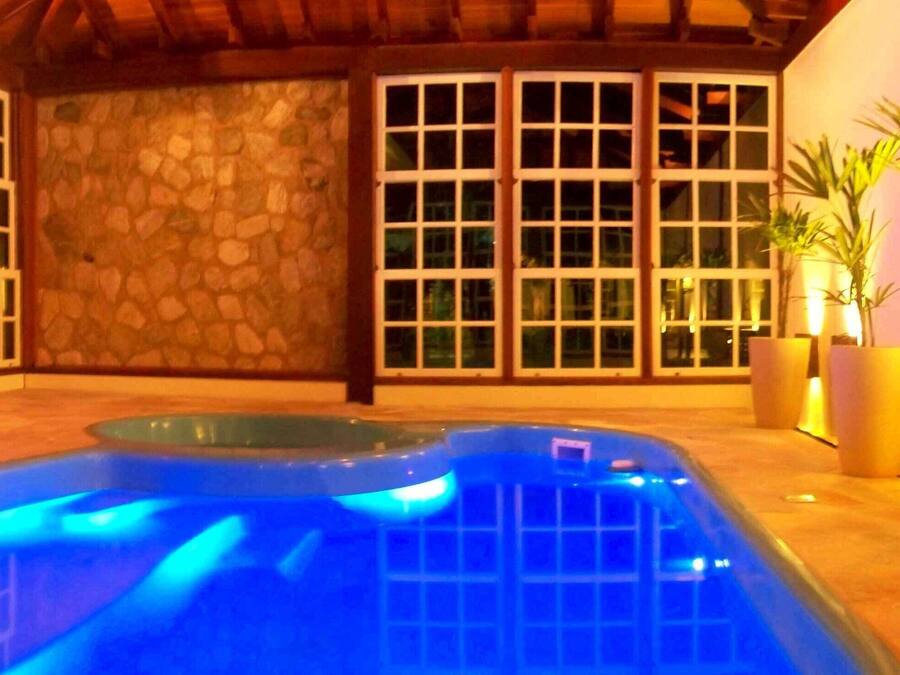 Un área de piscina con una pared de piedra y grandes ventanales.