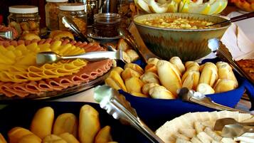 A buffet table with various food items including bread, fruits, and a large bowl of soup.