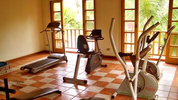 Un gimnasio con equipamiento de ejercicio, incluyendo cintas de correr, una elíptica y una bicicleta estática.