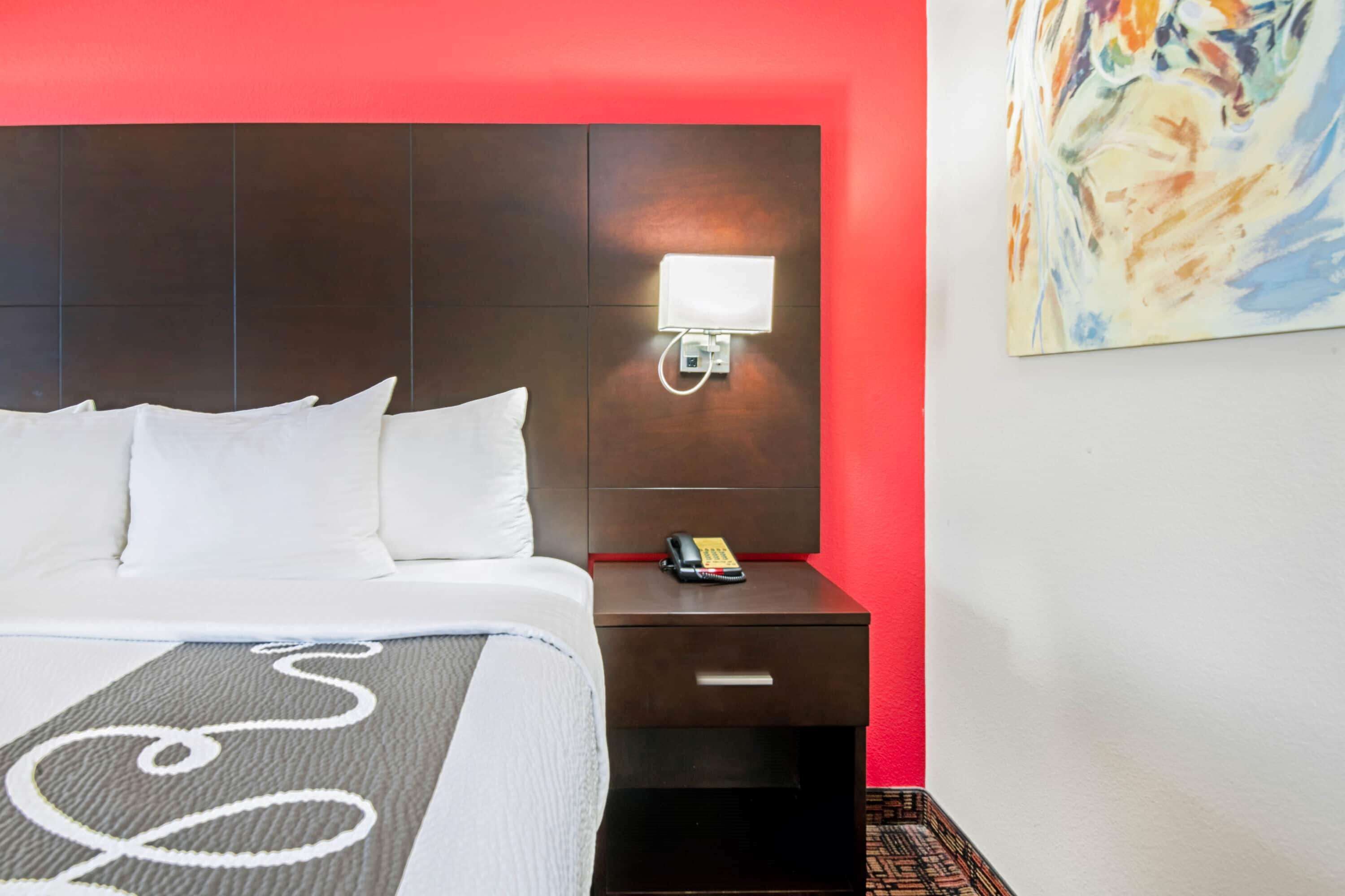 Habitación de hotel con una cama grande, una mesita de noche con teléfono y un cuadro en la pared.