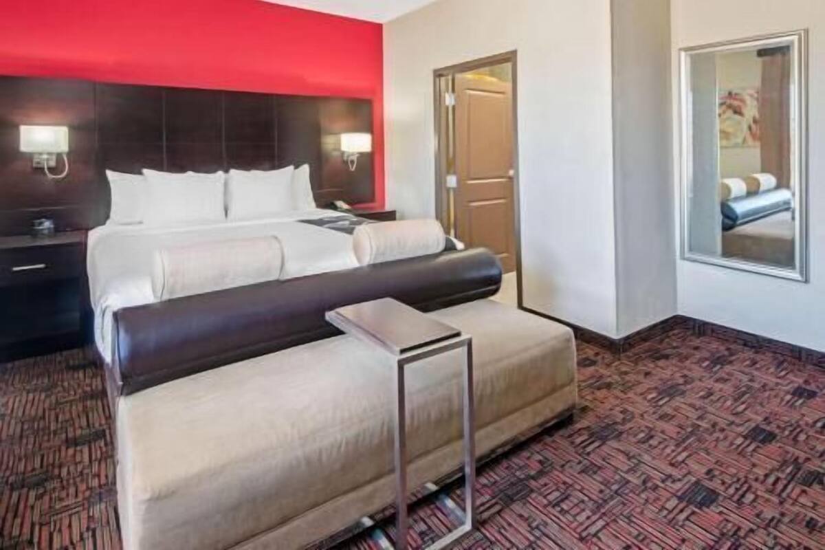 A hotel room with a bed, a desk, a chair, and a large mirror.