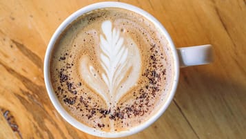 Une tasse de café ornée d’un motif en latte art, posée sur une surface en bois.