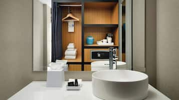 A modern bathroom with a large mirror, a round sink, and a wooden vanity.