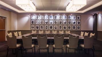 Une salle de conférence avec une longue table, de nombreuses chaises et des tableaux encadrés accrochés au mur.