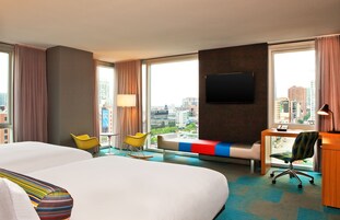 Habitación de hotel con una cama grande, un escritorio, una silla y un televisor.