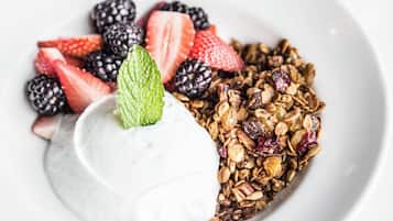 Een nagerechtenbord met een bolletje witte room en een mengsel van granola en bessen.