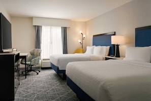 A hotel room with two beds, a desk, a chair, a lamp, and a TV. - Hampton Inn Thomson (Thomson)