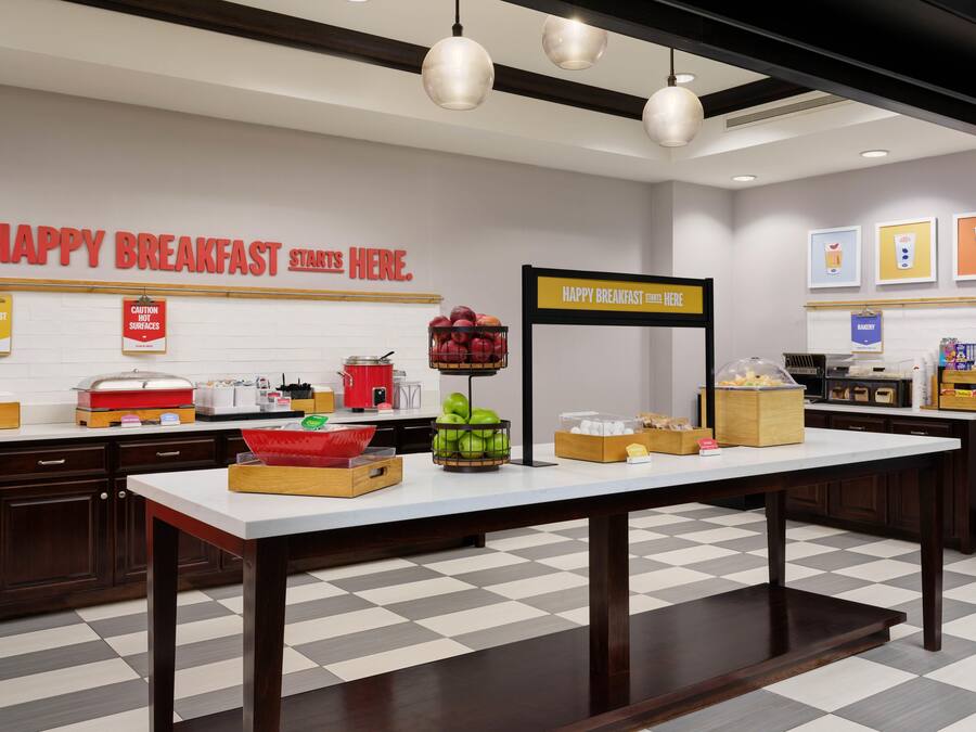 Uma área de café da manhã com balcão, eletrodomésticos de cozinha e uma placa que diz 'HAPPY BREAKFAST STARTS HERE'.