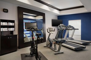 Una palestra con attrezzature per esercizi, tapis roulant, ellittica e cyclette.