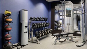 Une salle de sport équipée de matériel d’exercice, d’un support pour les squats et d’un banc.