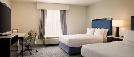 A hotel room with two beds, a desk with a chair, a TV, and a window with curtains.