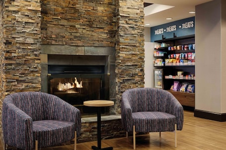 A stone fireplace with two upholstered chairs and a small table.. Hampton Inn Thomson