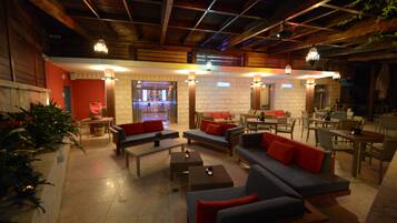 Eine geräumige Lobby mit mehreren Sitzbereichen, darunter Sofas und Sessel, und einem Barbereich im Hintergrund.