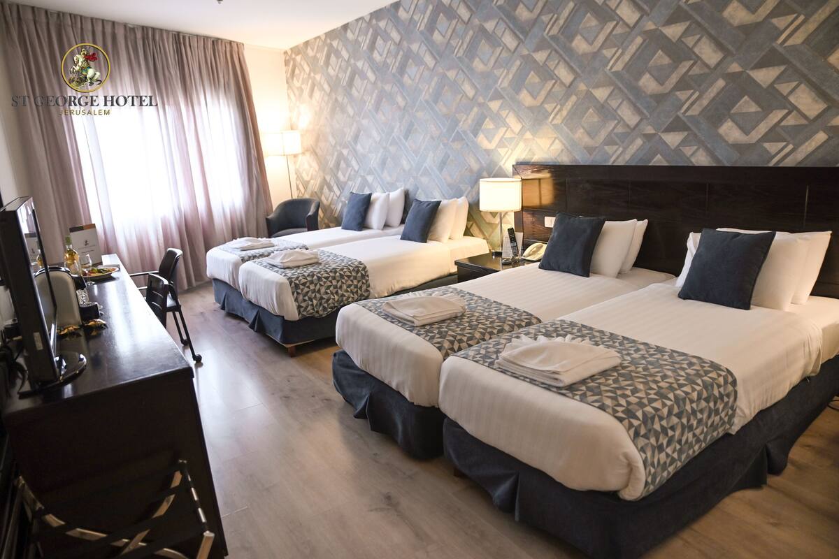 A hotel room with two beds, a desk with a computer, and a chair.