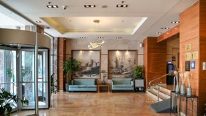 Un vestíbulo moderno con una recepción, dos zonas de estar, una escalera y un mural grande en la pared.