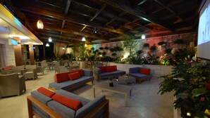 Amplio espacio interior con sofás, mesas y plantas en macetas.