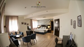 Una habitación de hotel con cama, sofá, escritorio y mesa de comedor.