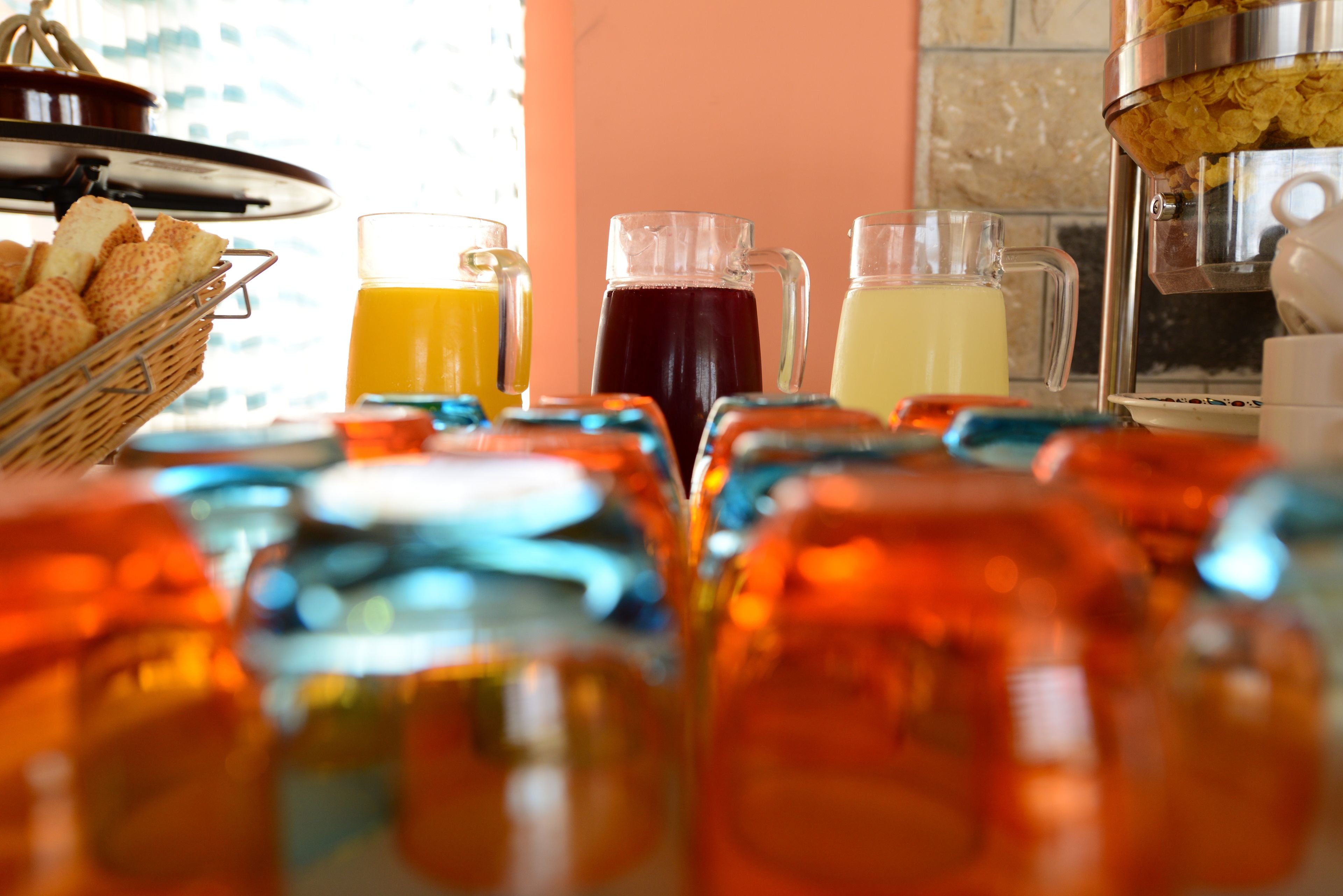 A breakfast setup with various beverages and a basket of bread.