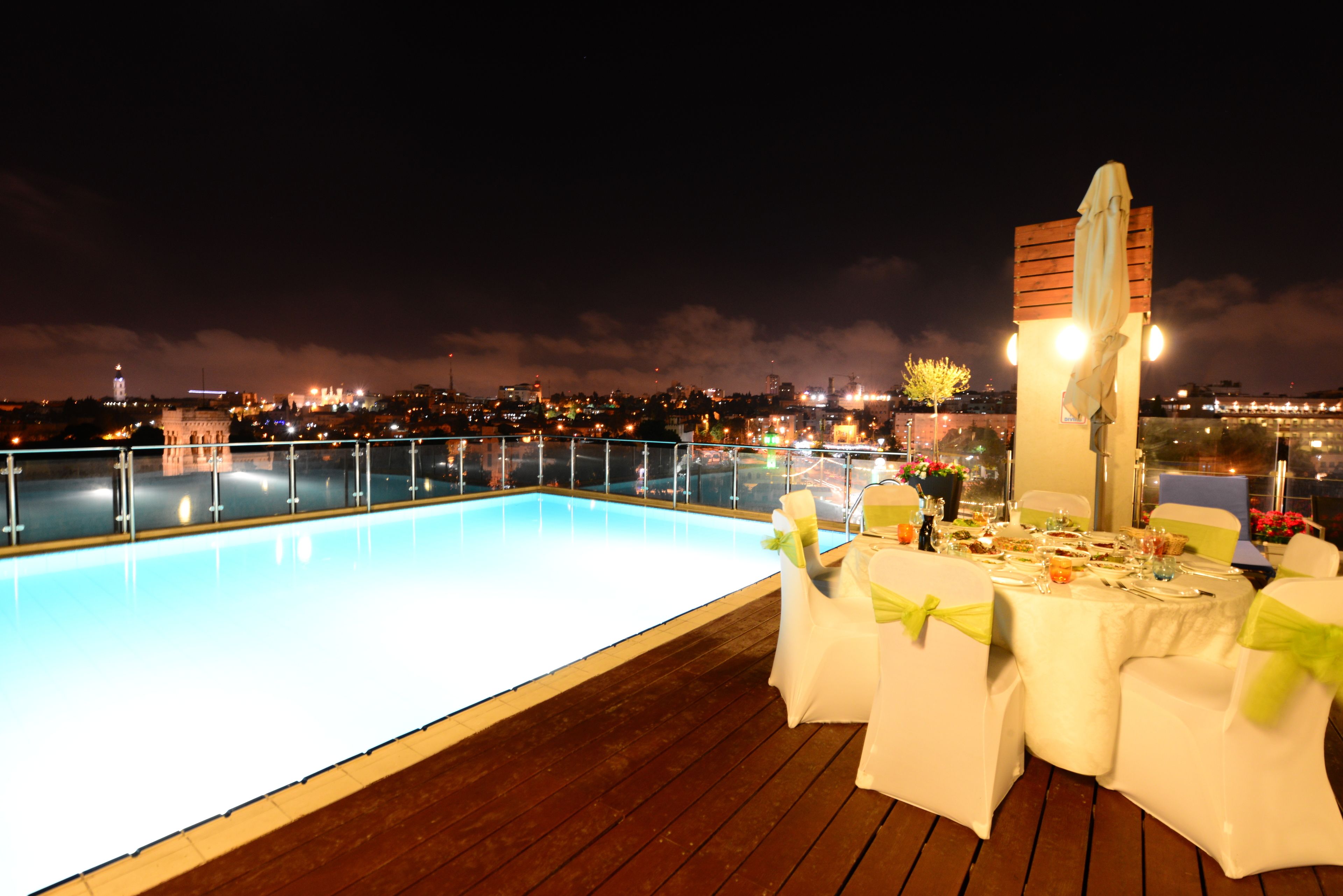A rooftop pool area with a dining setup.