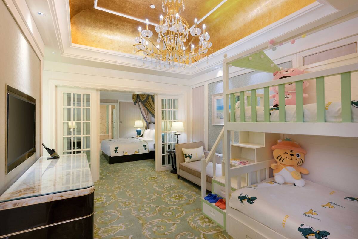 A hotel room with bunk beds, a television, and a chandelier.