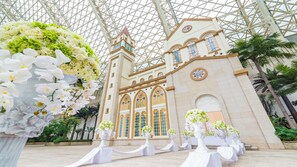 A building with a glass roof and a tower, surrounded by potted plants and flower arrangements. - InterContinental Chengdu Global Center by IHG (Chengdu)