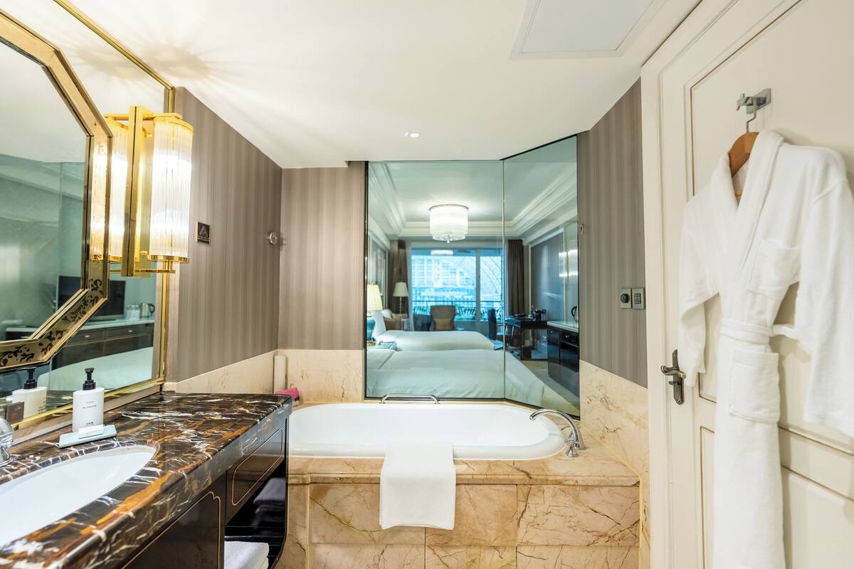 A modern bathroom with a marble sink, a freestanding bathtub, and a large mirror.