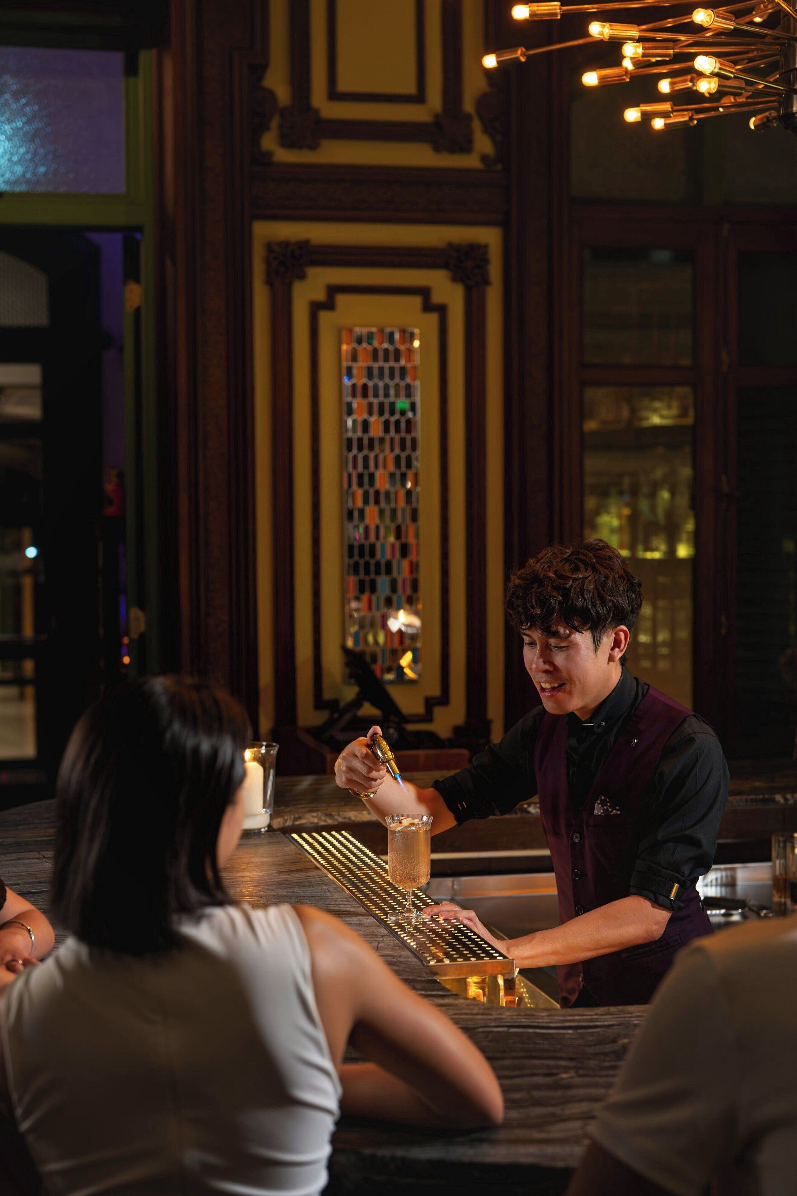 A bar setting with a bartender preparing a drink.