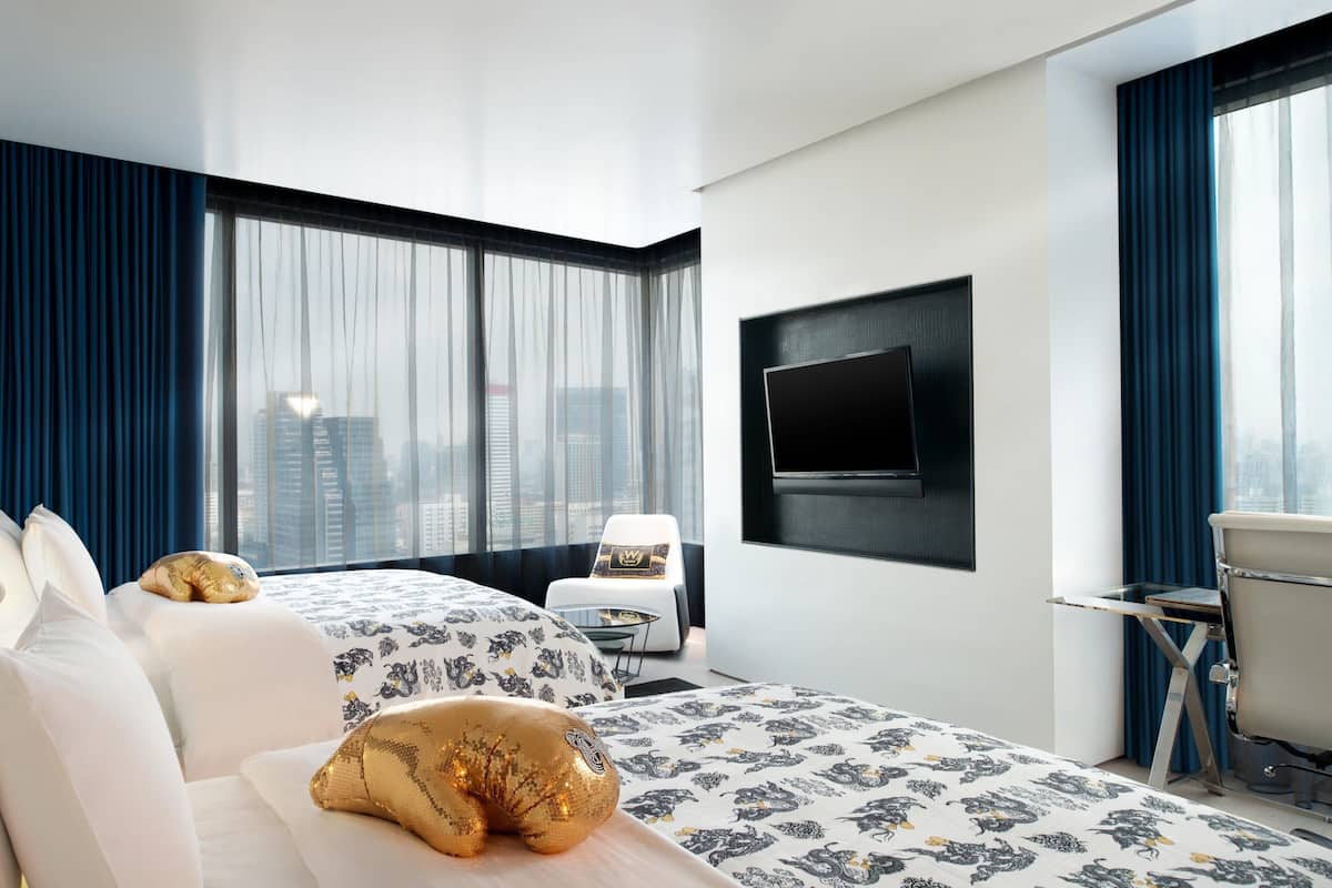 A modern hotel room with a large bed, a desk, and a TV mounted on the wall.