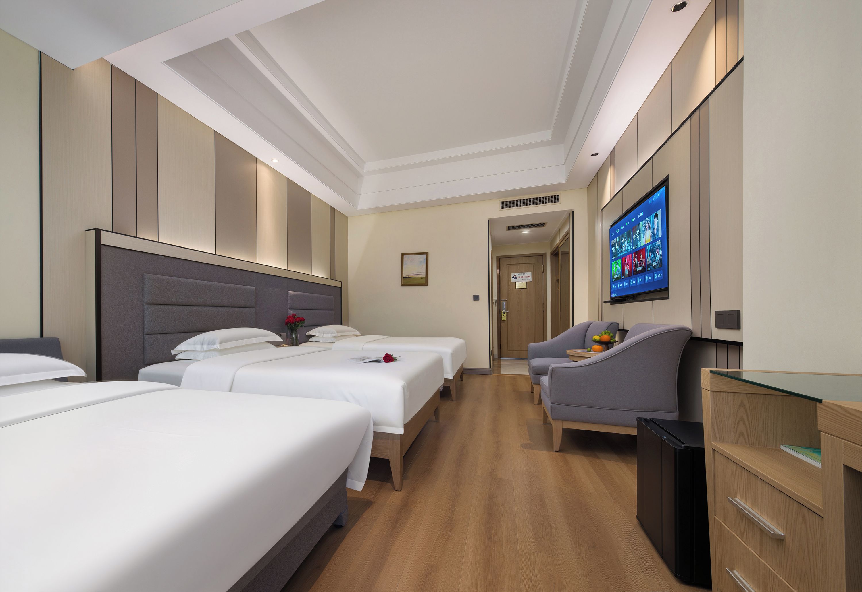 A hotel room with two beds, a television, a desk, and a chair.