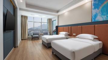 A hotel room with two beds, a TV, a view of mountains, and a cityscape.