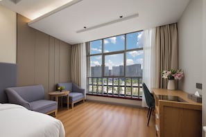 A hotel room with a large window, a bed, a desk, and a seating area. - Ramada by Wyndham Zhangjiajie Tianmen Mountain (Zhangjiajie)