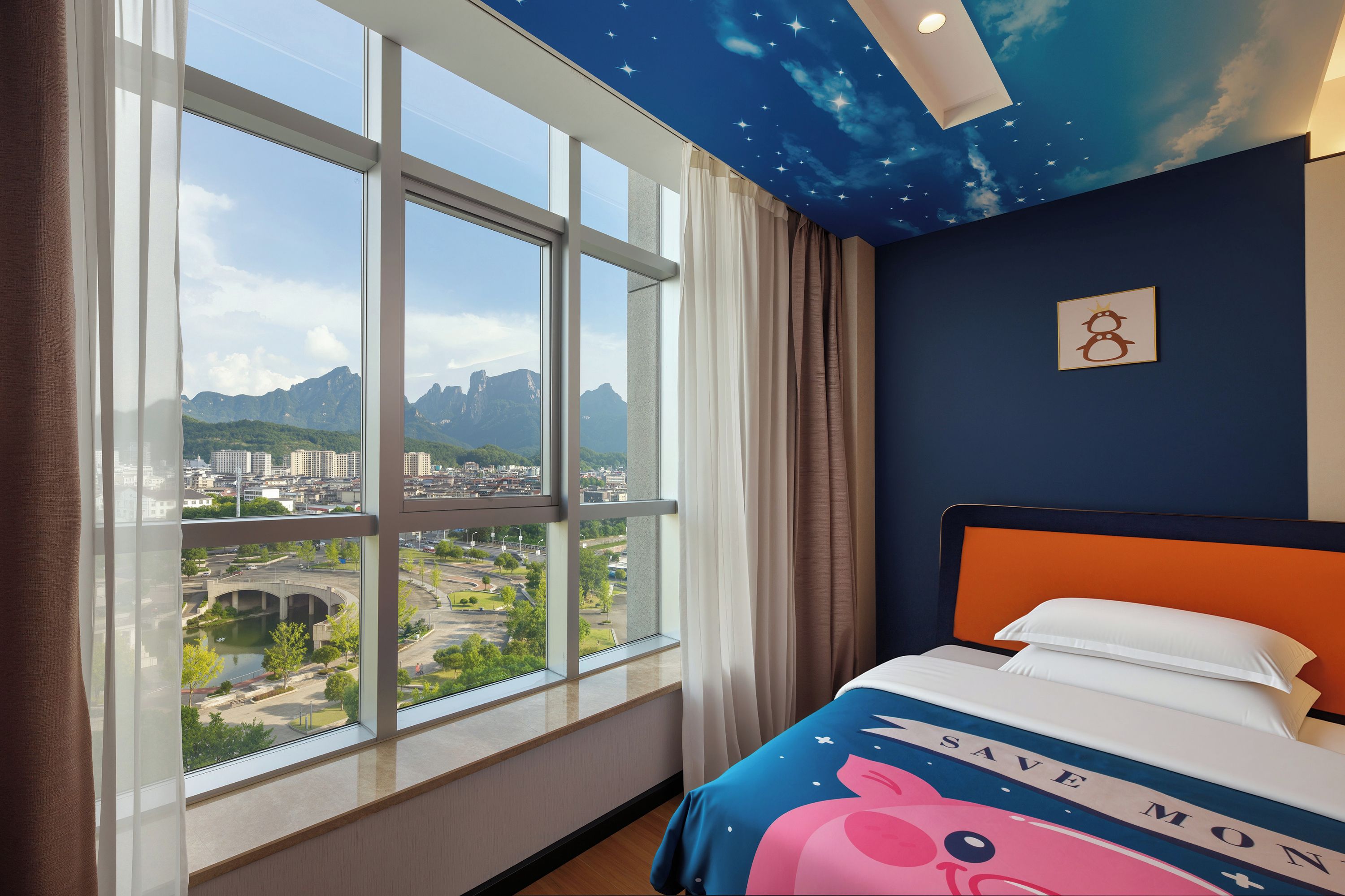 Een hotelkamer met een groot raam en uitzicht over de stad, een bed met een kleurrijk hoofdeinde en een plafond met een sterrenmotief.