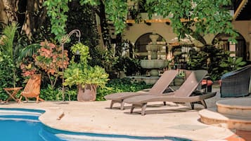 Una piscina al aire libre, sombrillas, sillones reclinables de piscina