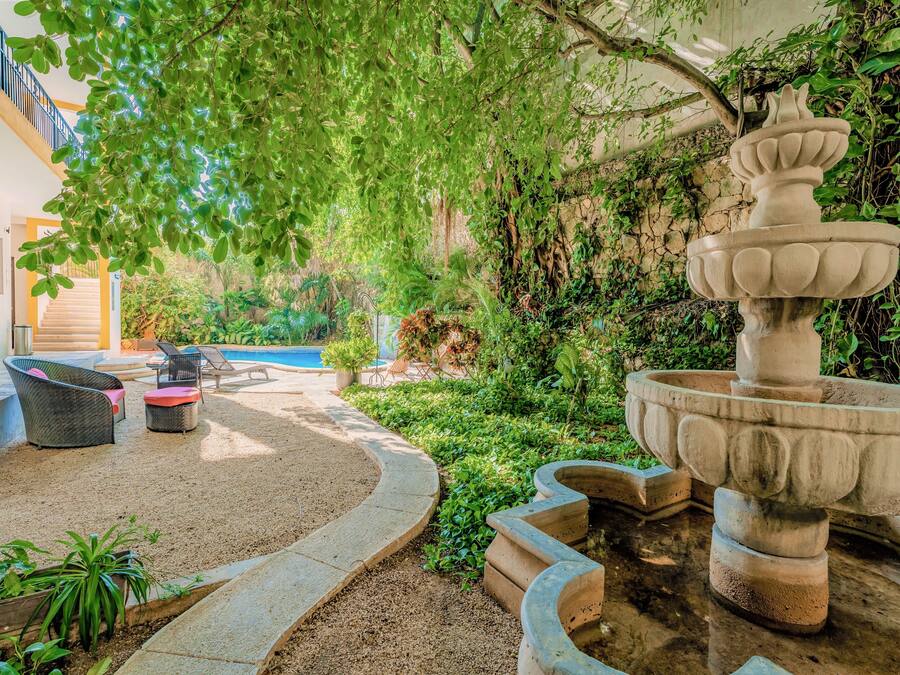 A courtyard with a stone fountain, outdoor seating, and a pool.