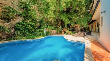 Una piscina al aire libre, sombrillas, sillones reclinables de piscina
