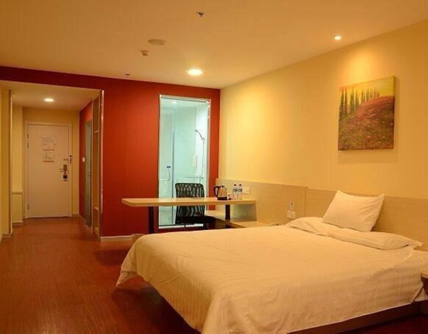 A hotel room with a bed, a desk, and a chair.