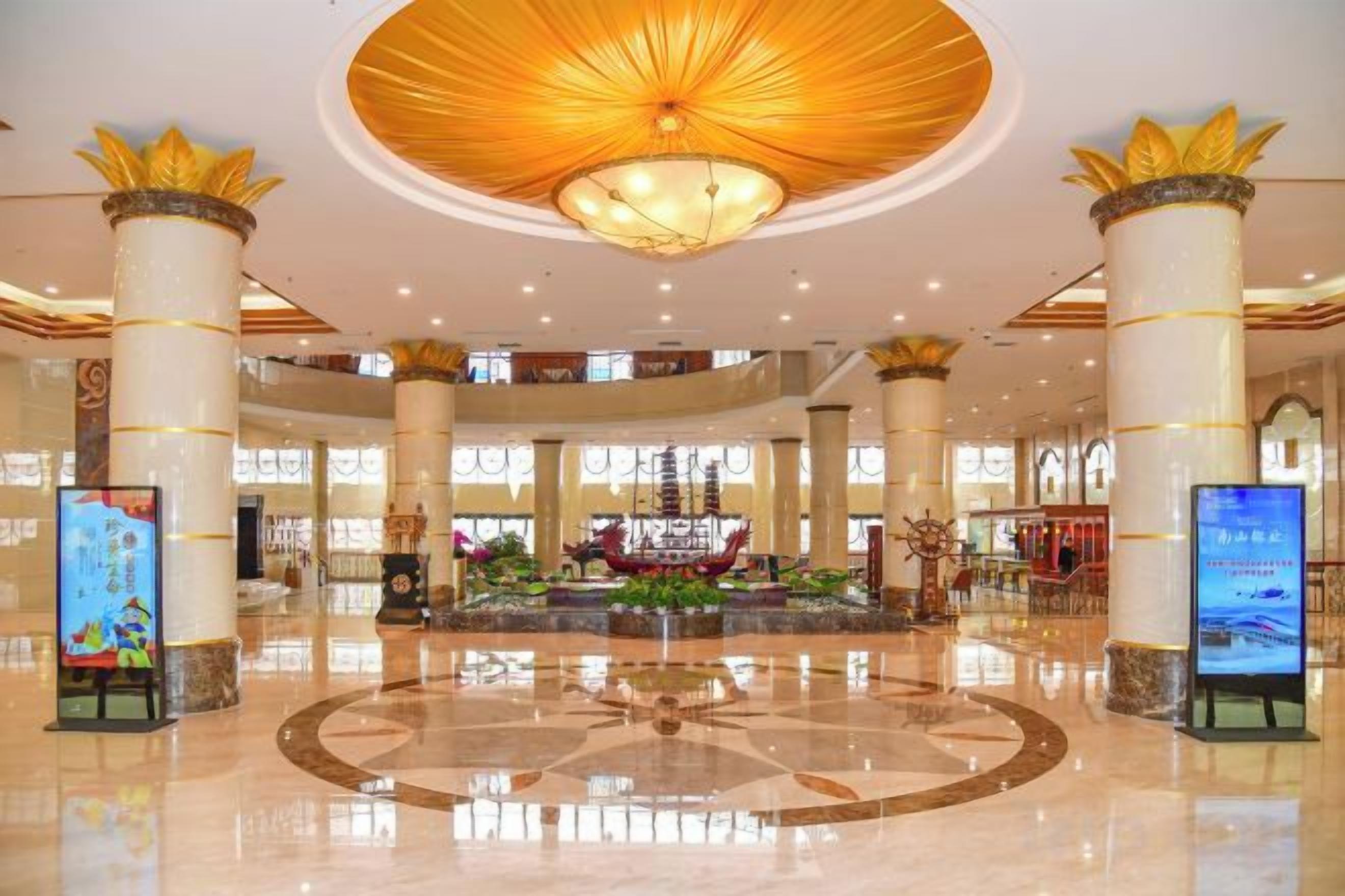 A spacious lobby with a central fountain, large columns, and a high ceiling with a decorative light fixture.