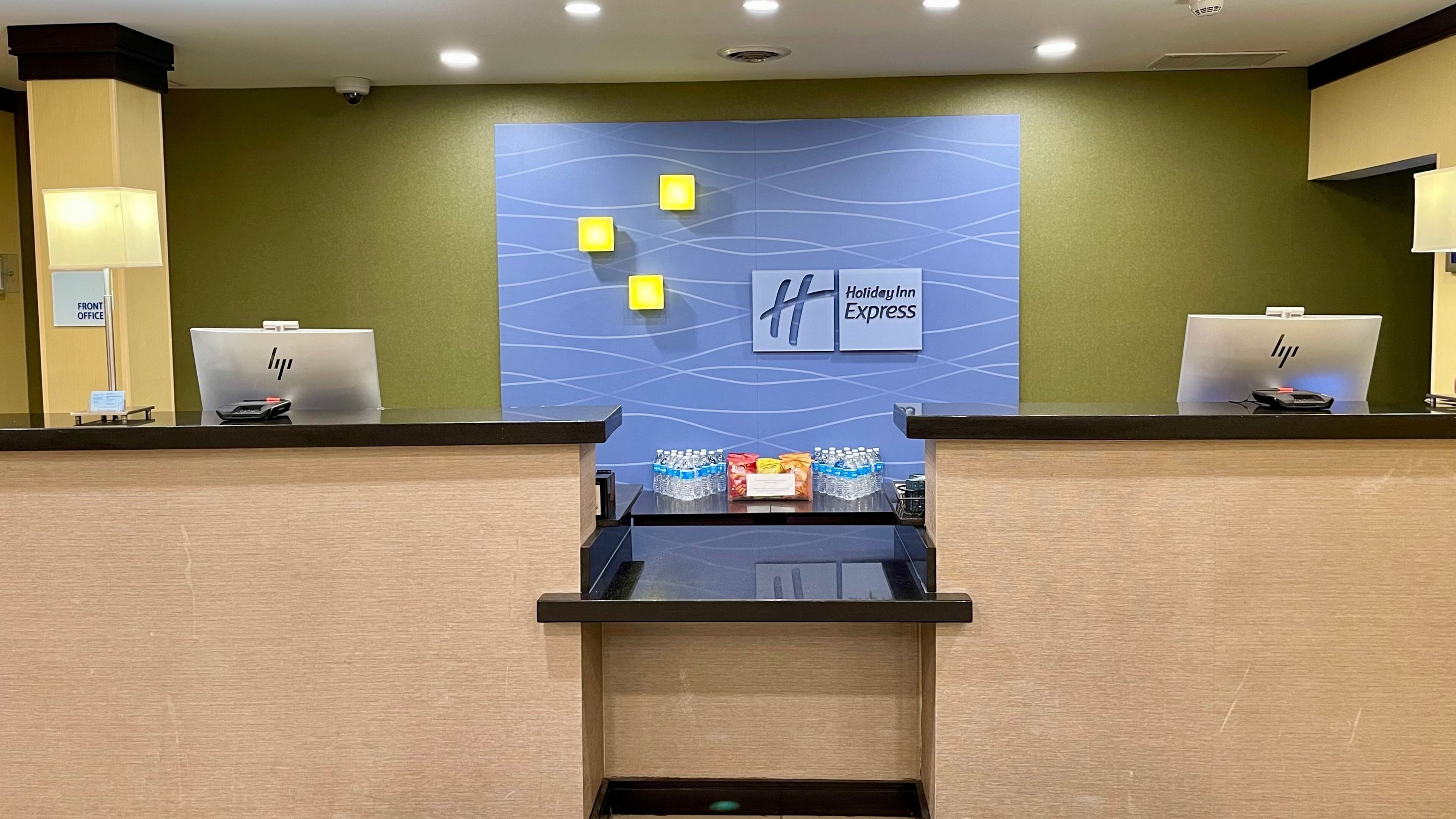 A hotel reception desk with a blue wall design, a HP computer, and a water dispenser.