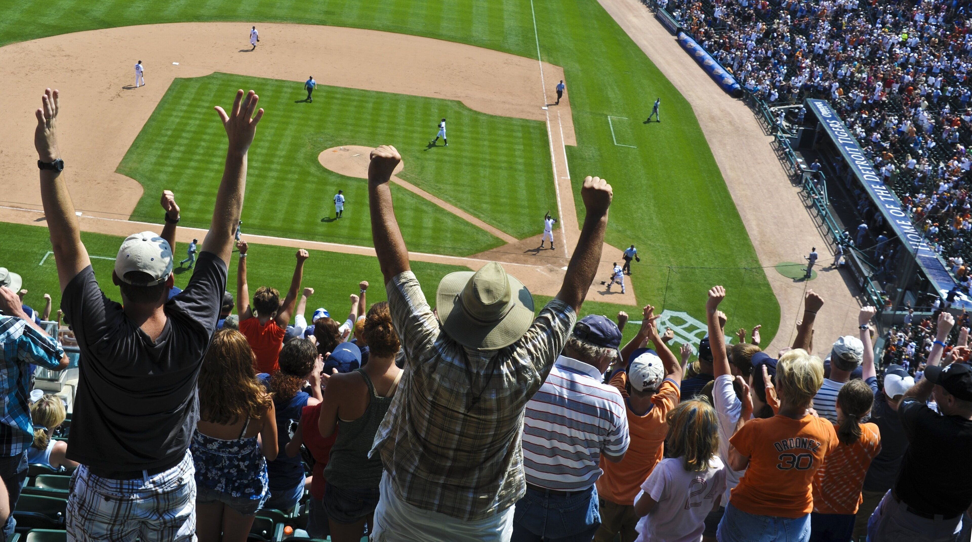 Un estadio con un campo de béisbol, espectadores y jugadores.