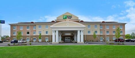 A large hotel with a central entrance, multiple floors, and a parking lot.