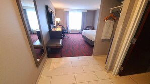Une chambre d’hôtel comprenant un lit, un bureau avec une chaise, une télévision et un miroir.