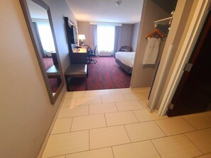 A hotel room with a bed, a desk with a chair, a TV, and a mirror. - Holiday Inn Express & Suites Utica by IHG (Utica)