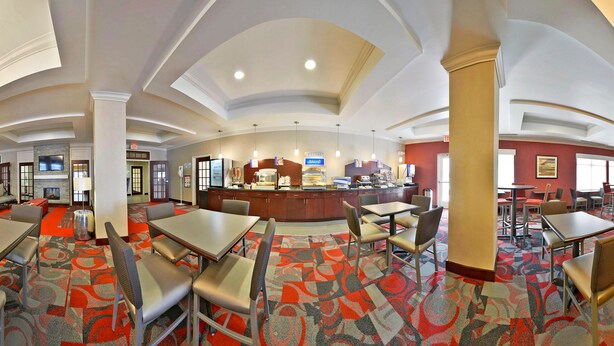 A hotel lobby with a reception desk, seating area, and a TV mounted on the wall.