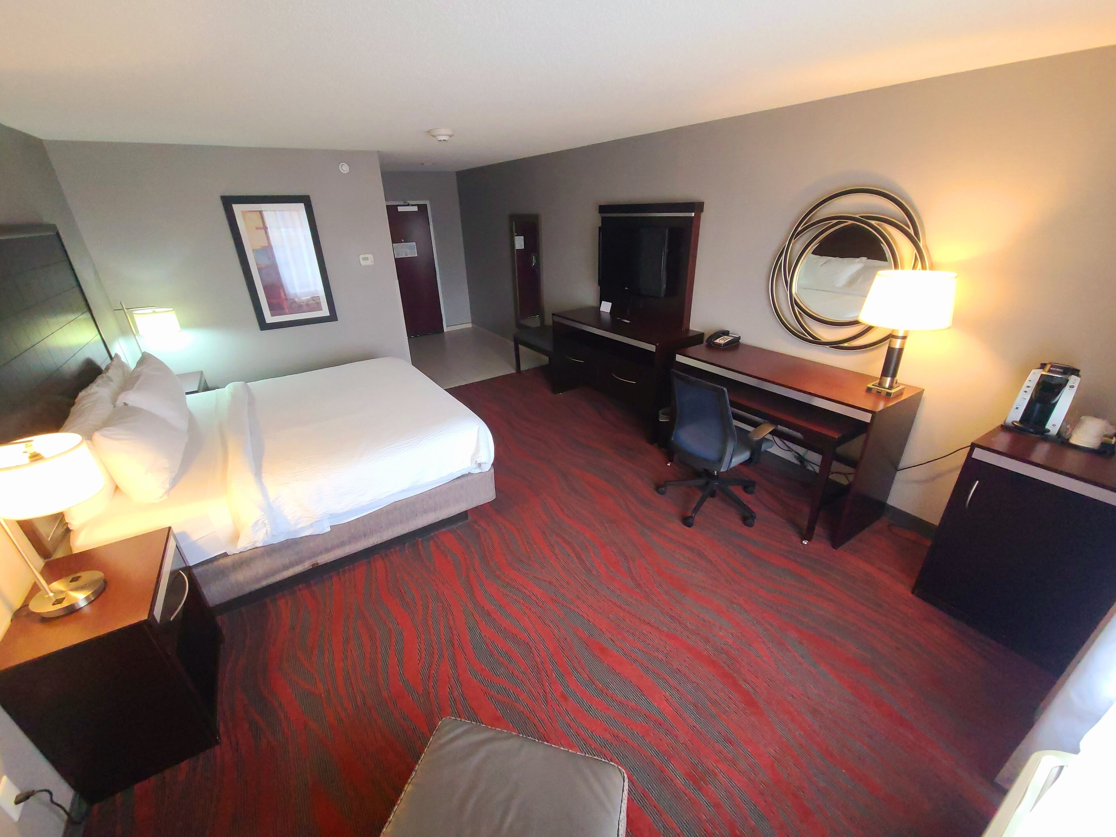 Habitación de hotel con cama, escritorio, silla y lámpara de escritorio.