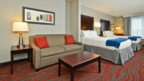 Une chambre d’hôtel avec un canapé, deux lits, une table et une moquette à motifs.