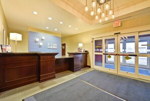 A reception area with a desk, a wall-mounted sign, and a set of revolving doors. - Holiday Inn Express & Suites Utica by IHG (Utica)