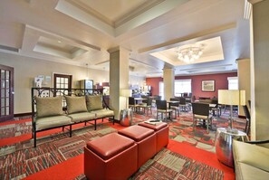 A hotel lobby with a sofa set, a red ottoman, a chandelier, and a patterned carpet. - Holiday Inn Express & Suites Utica by IHG (Utica)