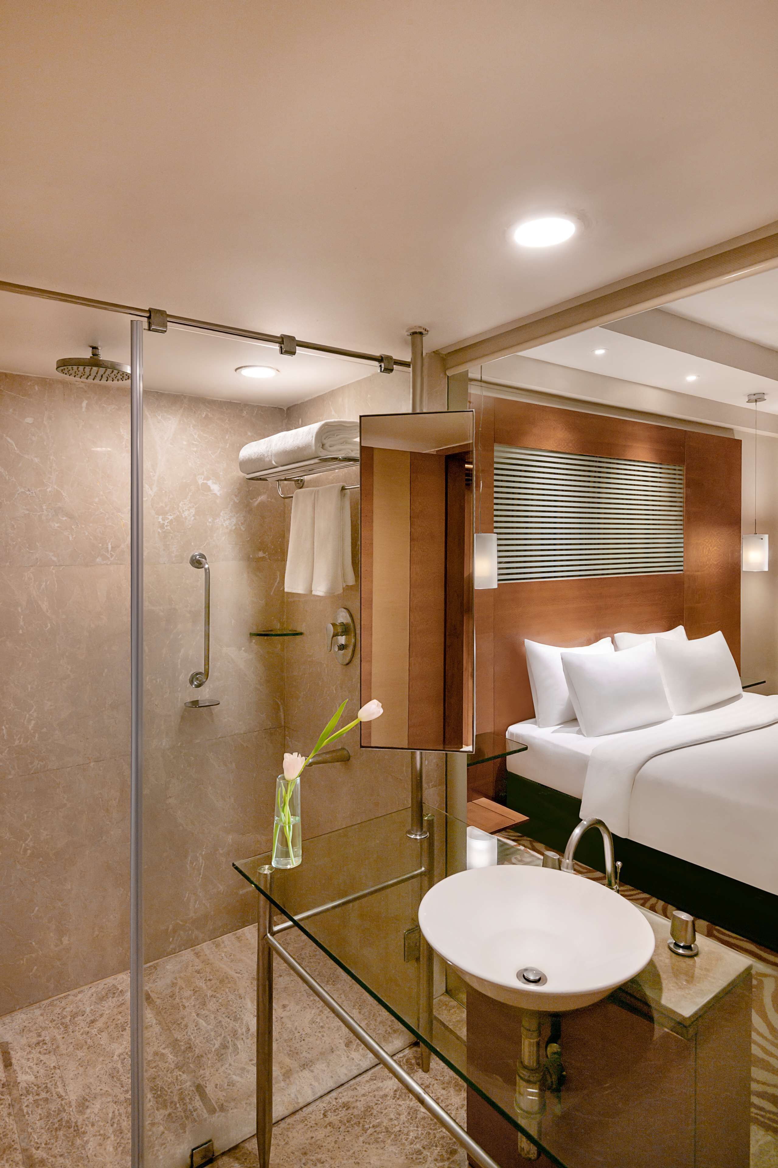 Un baño moderno con ducha envuelta en vidrio, lavamanos de vidrio y un espejo grande.