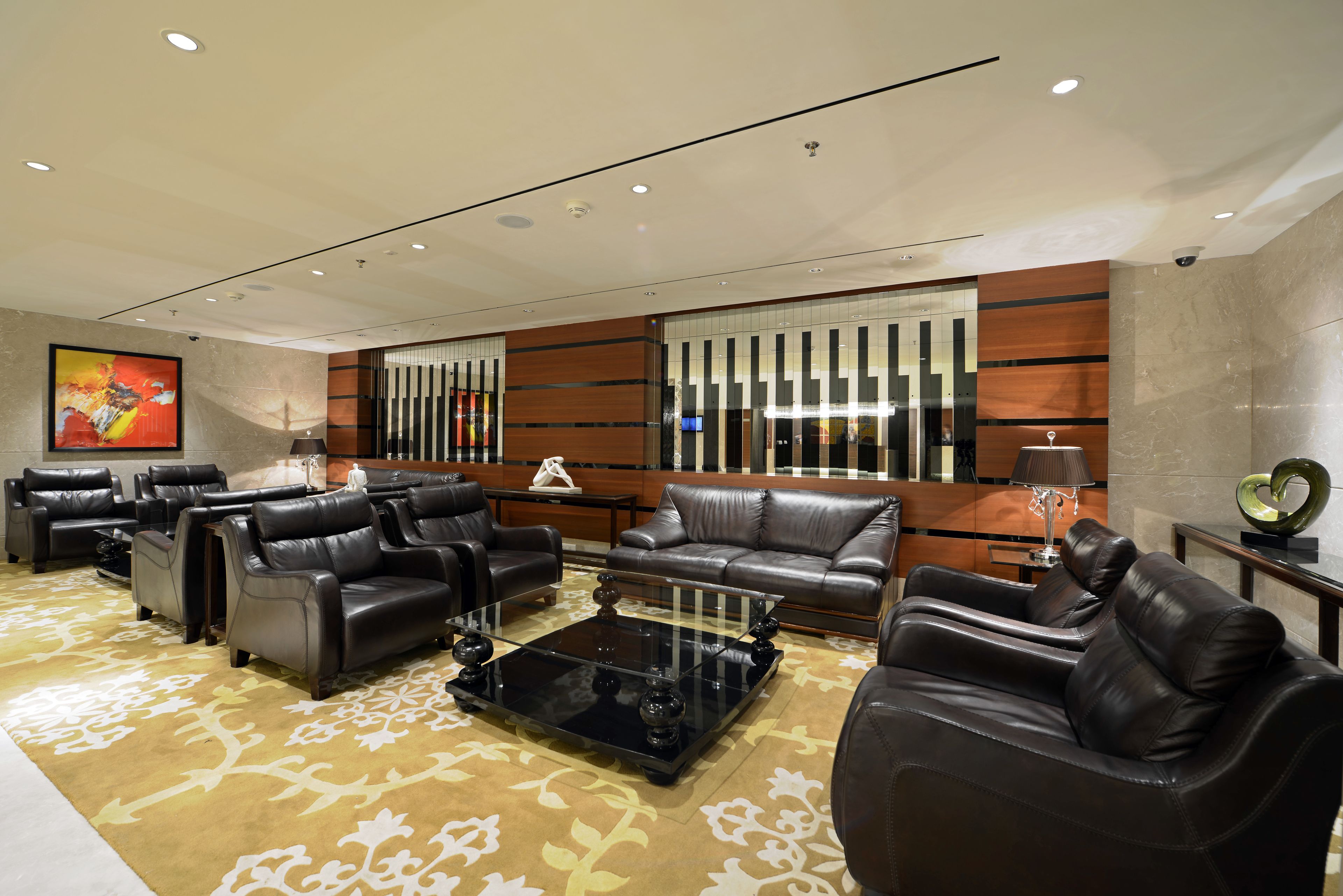 A modern living room with leather sofas, a glass coffee table, and a patterned carpet.